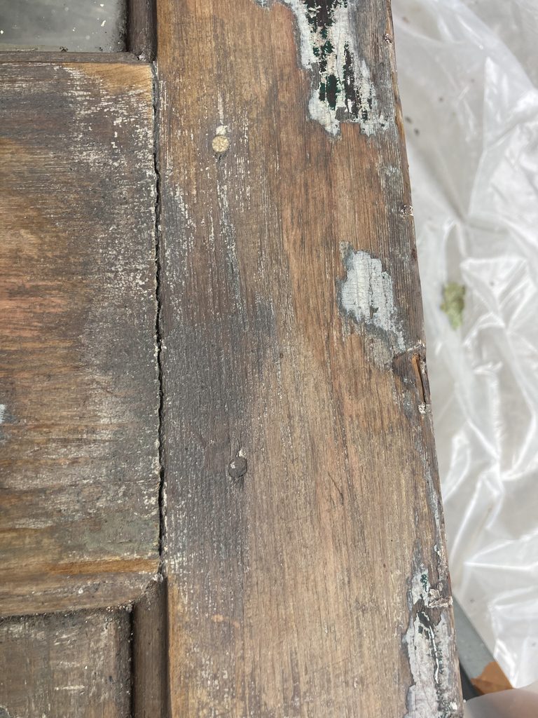 Close-up of a stripped wood door panel edge with a visible seam.