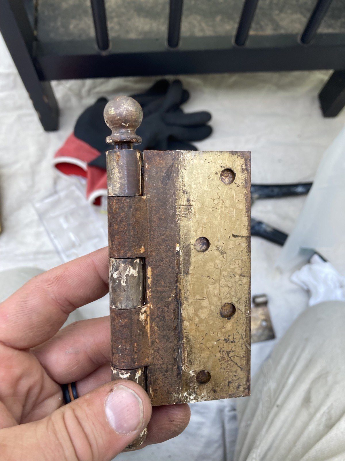 Original period ball-tip brass hinge held before cleaning and reinstallation