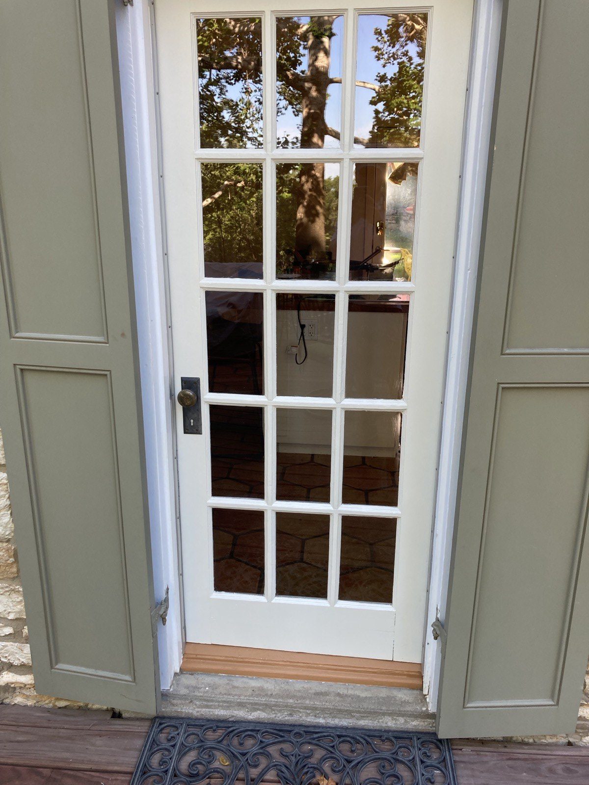 Restored twelve-light door installed in stone surround painted sage green with white trim