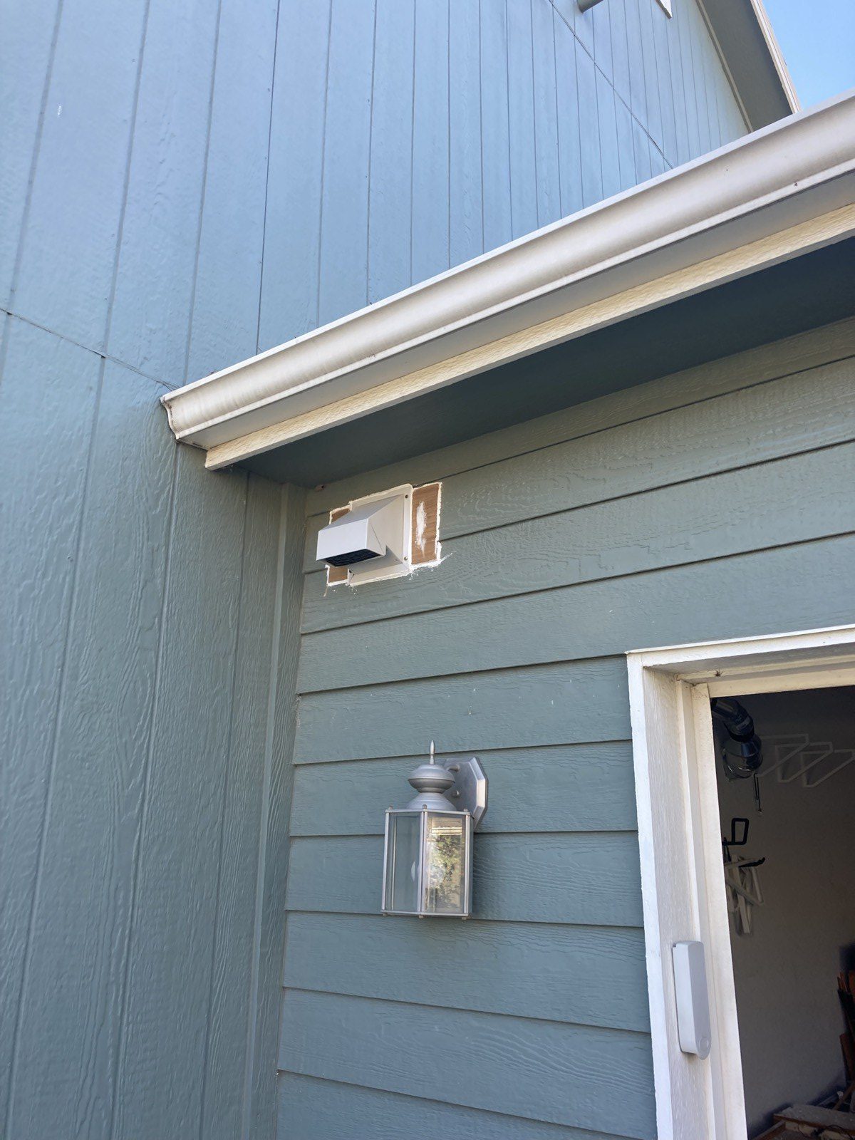 New white vent cap installed in the siding above the garage entrance.